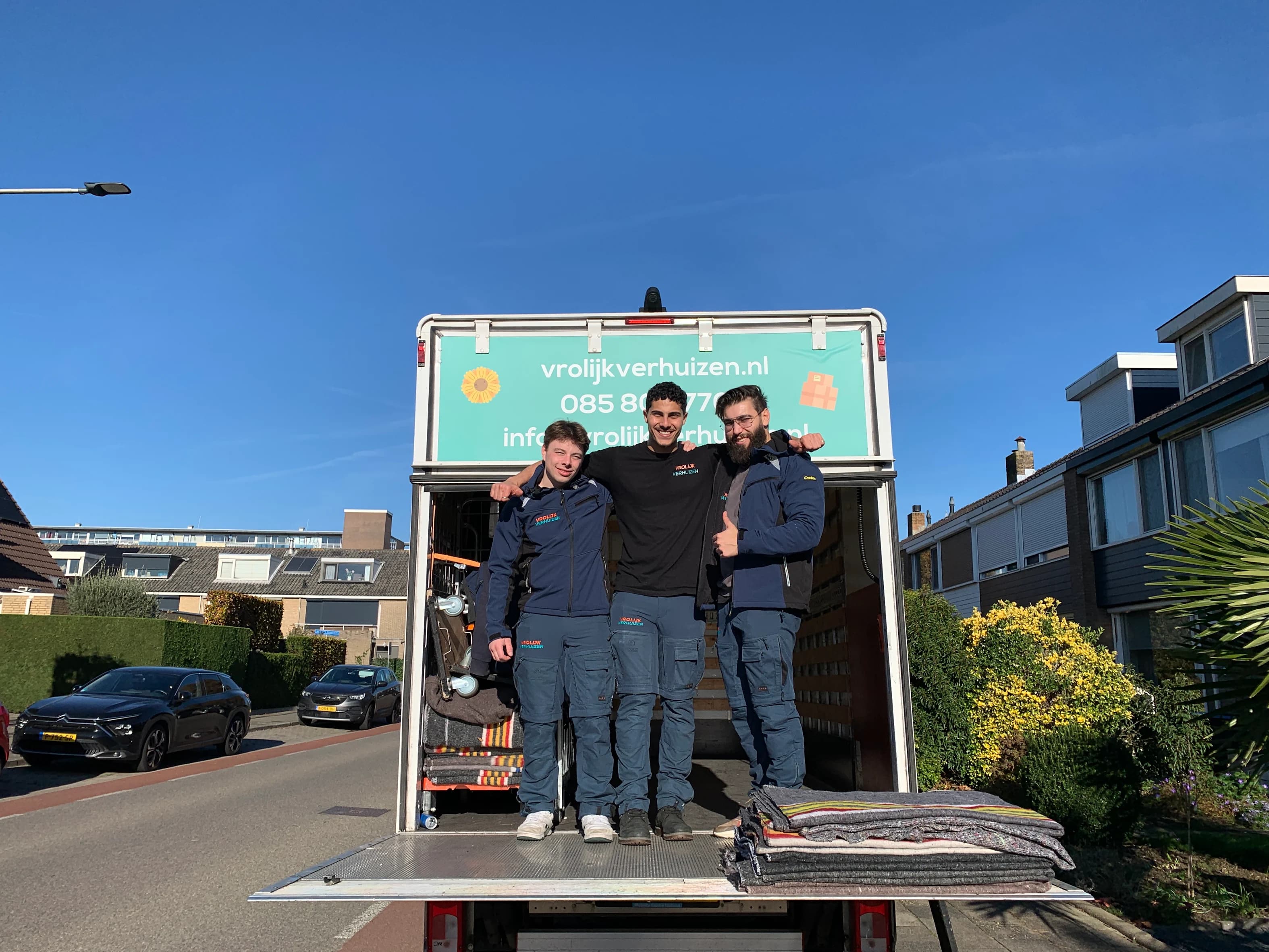 Drie Vrolijk Verhuizen crewleden op de laadklep in Alphen aan den Rijn