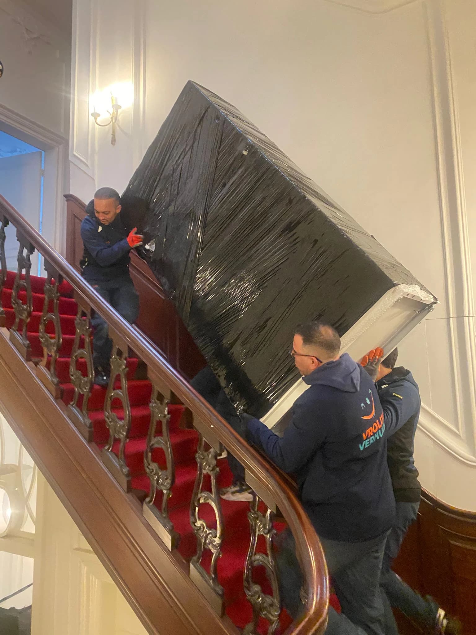 Vrolijk Verhuizen crew members carrying a large piece of furniture